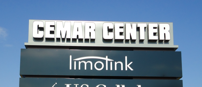 Outdoor sign with bold white letters reading CEMAR CENTER above a panel displaying the limolink logo, set against a clear blue sky.